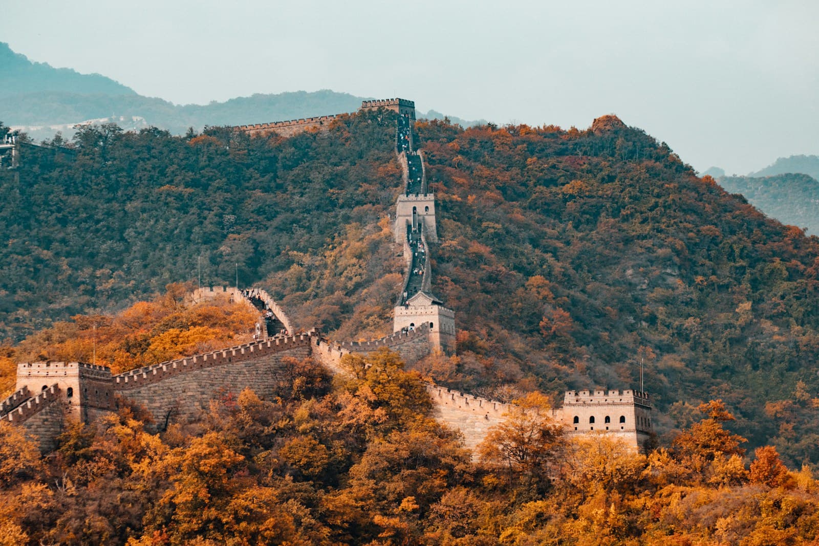 The Great Wall of China winding across green mountains at sunrise